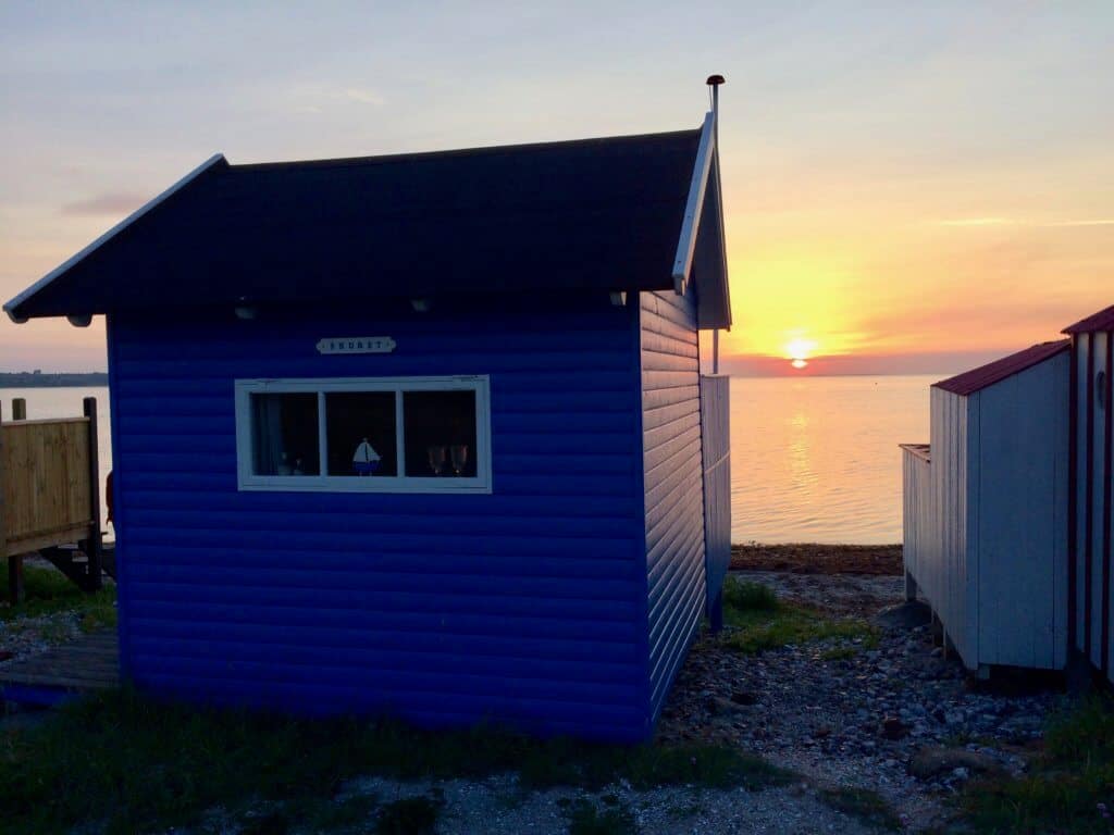 A small hut stands on the shore during sunset in Aero, Denmark.