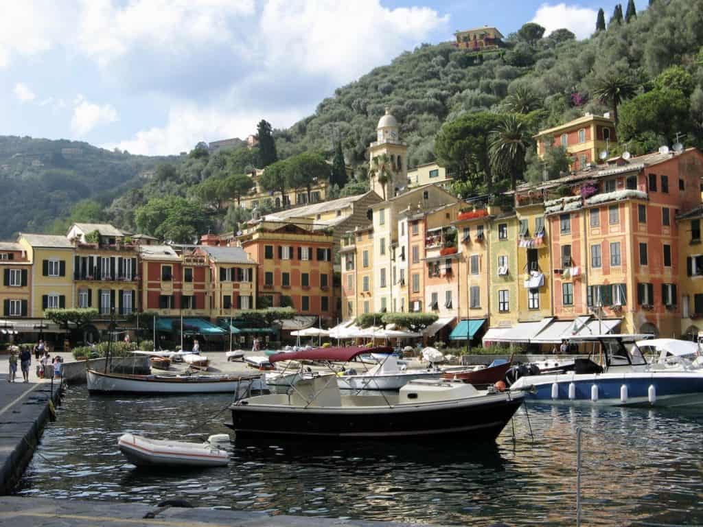 Small boats are docked in the Portofino harbor with colorful buildings in the background