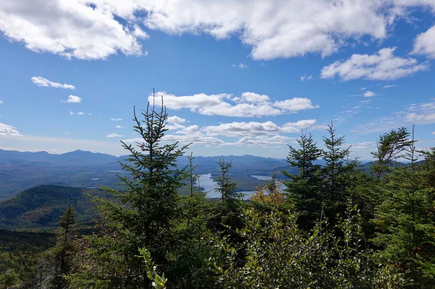 A view of trees in the foreground and Lake Placid Lake in the background from Whiteface Veteran's Memorial Highway.