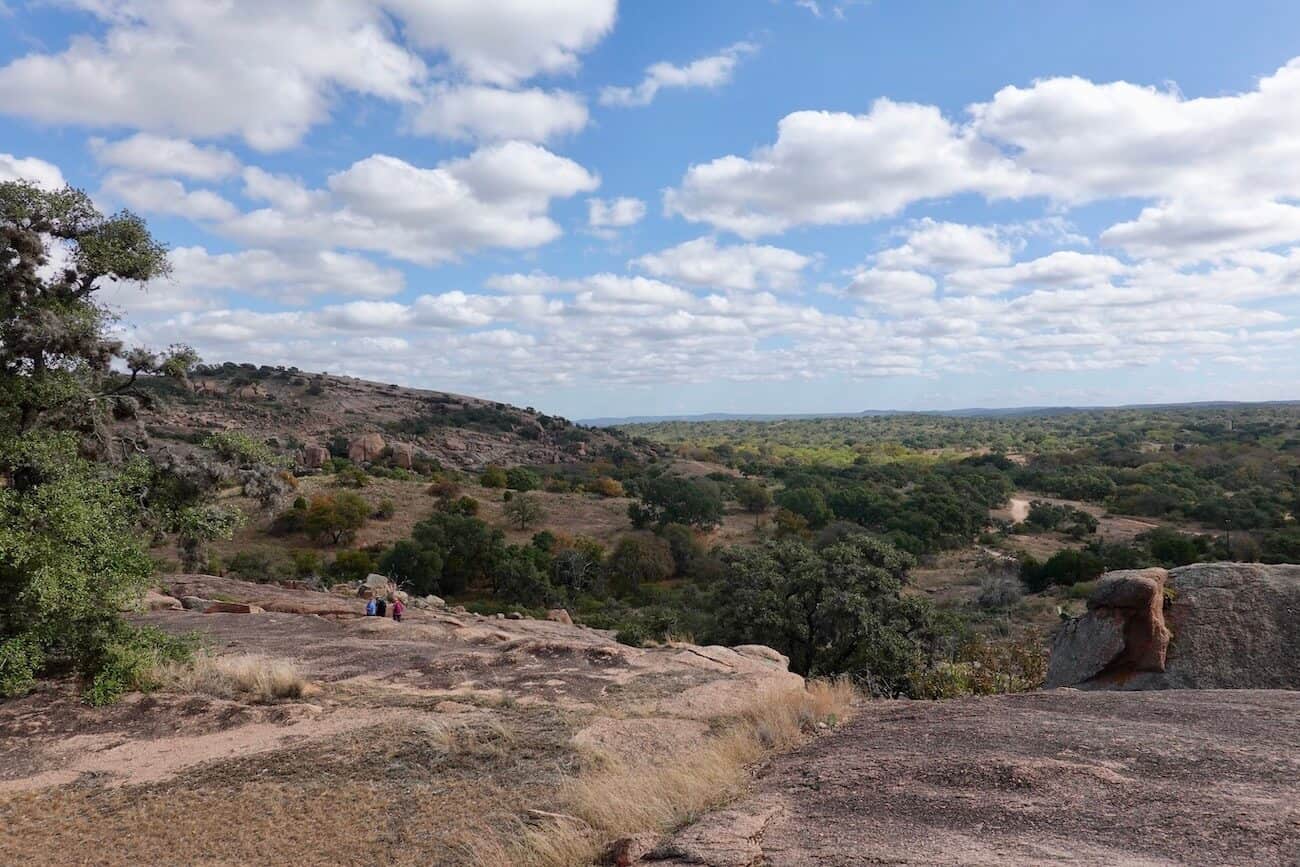 An expansive view of some rock formations at Enchanted Rock and the natural scenery in the distance.