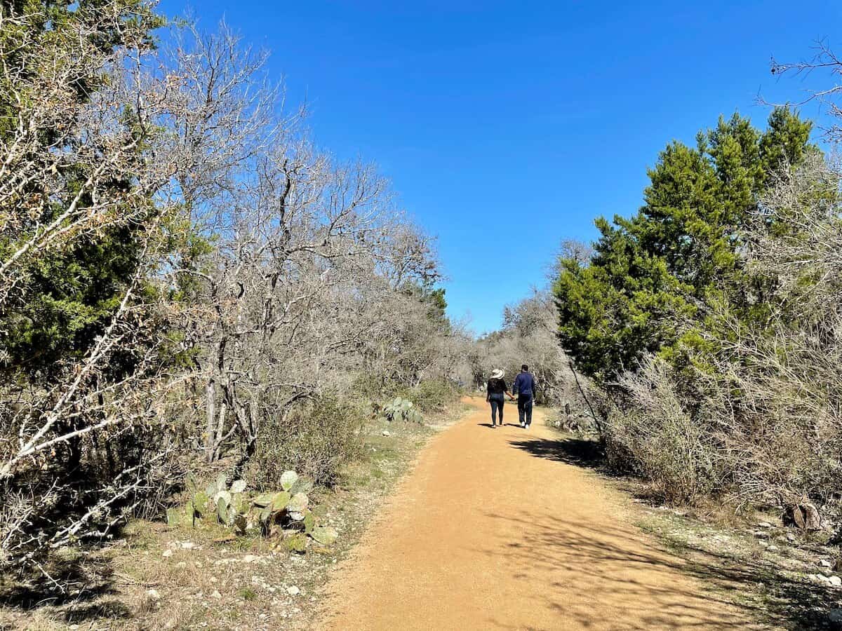 A couple walks along a dirt trail at Hardberger Park.