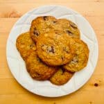 Cookies with potato chips and chocolate chips sit on a round, white plate.