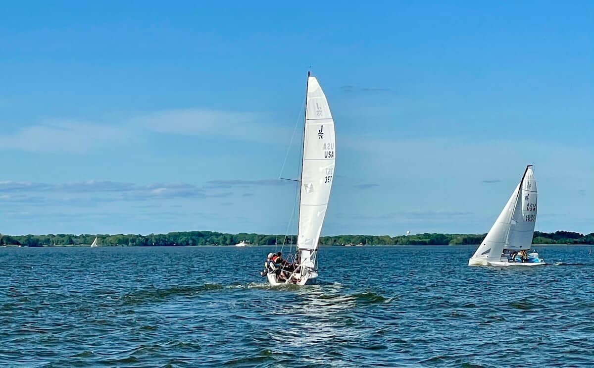 Two small sailboats glide in the Chesapeake Bay.