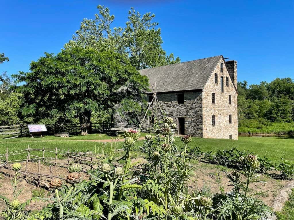 A brick building with a wooden irrigation system stands in a grassy field.