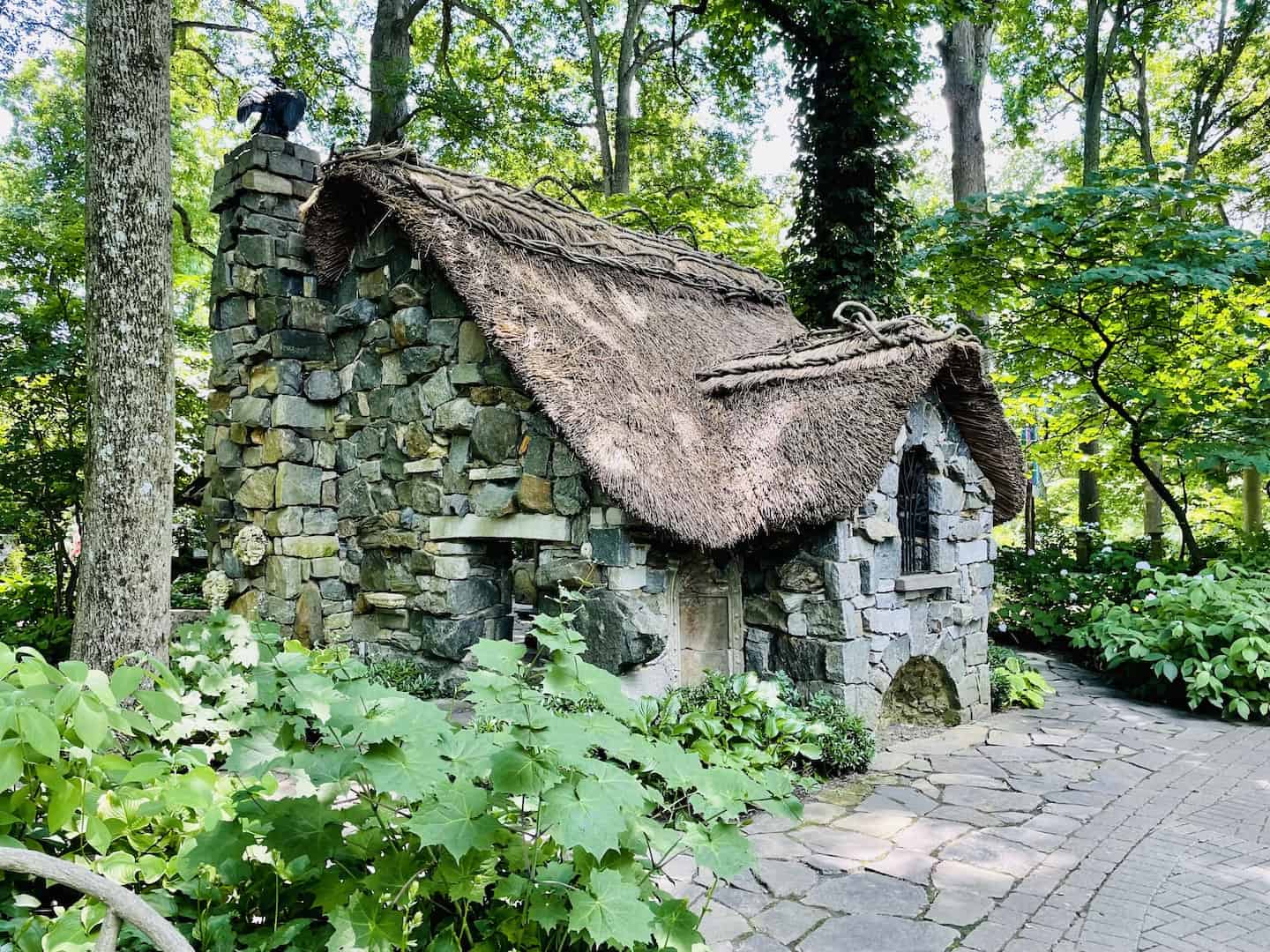A stone cottage with a thatched room sits in woods at Winterthur.