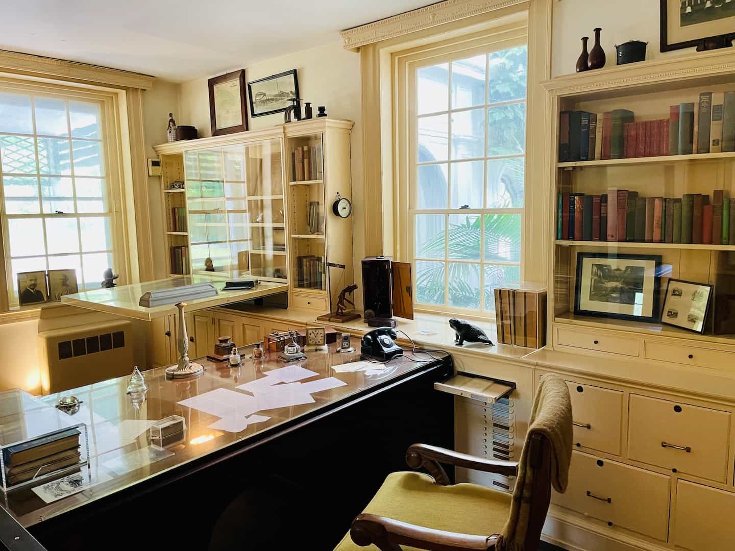 A black rotary phone sits on a wooden desk next to wooden bookcases and file cabinets at Longwood Gardens, PA.