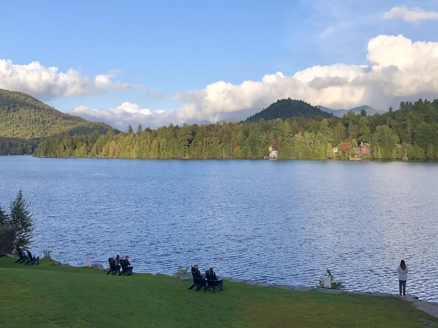 A view of people sitting in chairs enjoying the evening view of Mirror Lake.