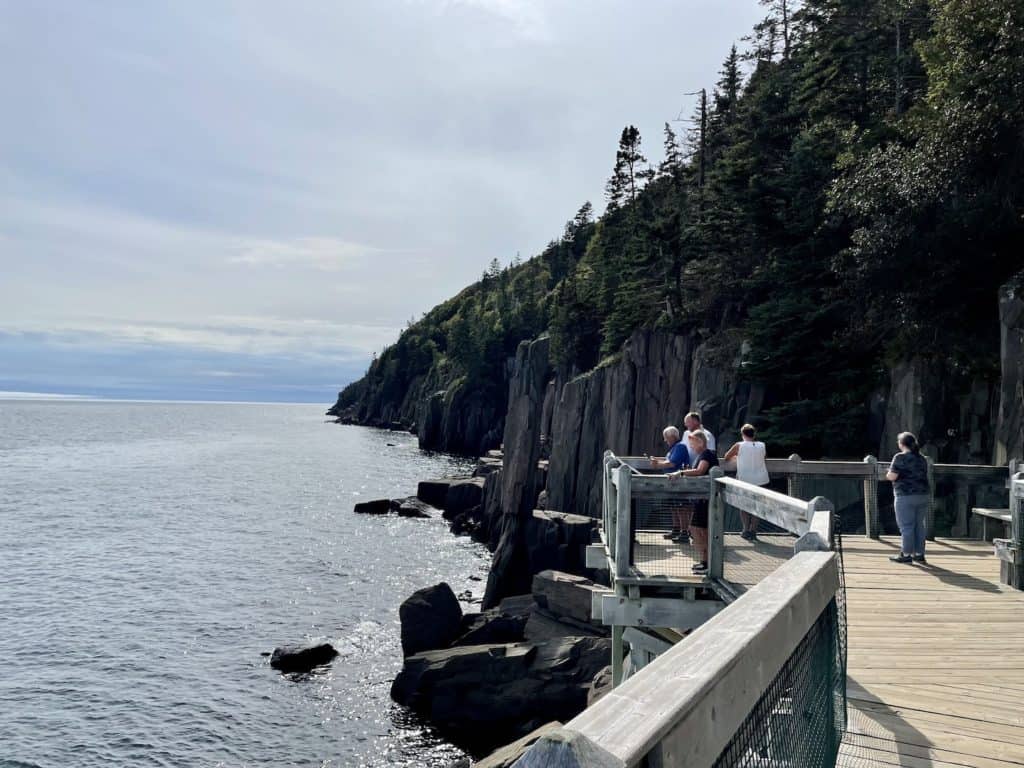 People stand on an observation deck to view Balancing Rock and read informational signs.