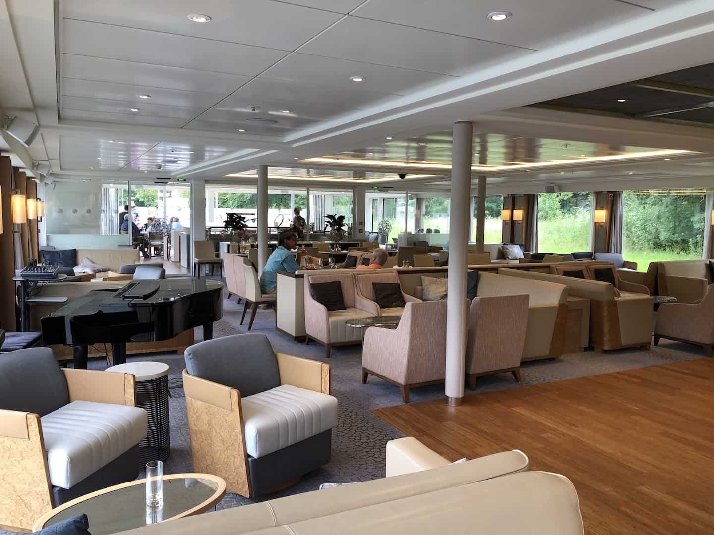 Upholstered sofas and chairs and a piano sit in a Viking river cruise lounge.