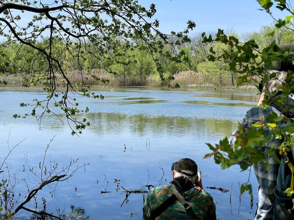 Two bird watchers take photographs of migratory birds across a large pond at John Heinz National Wildlife Refuge in PA.
