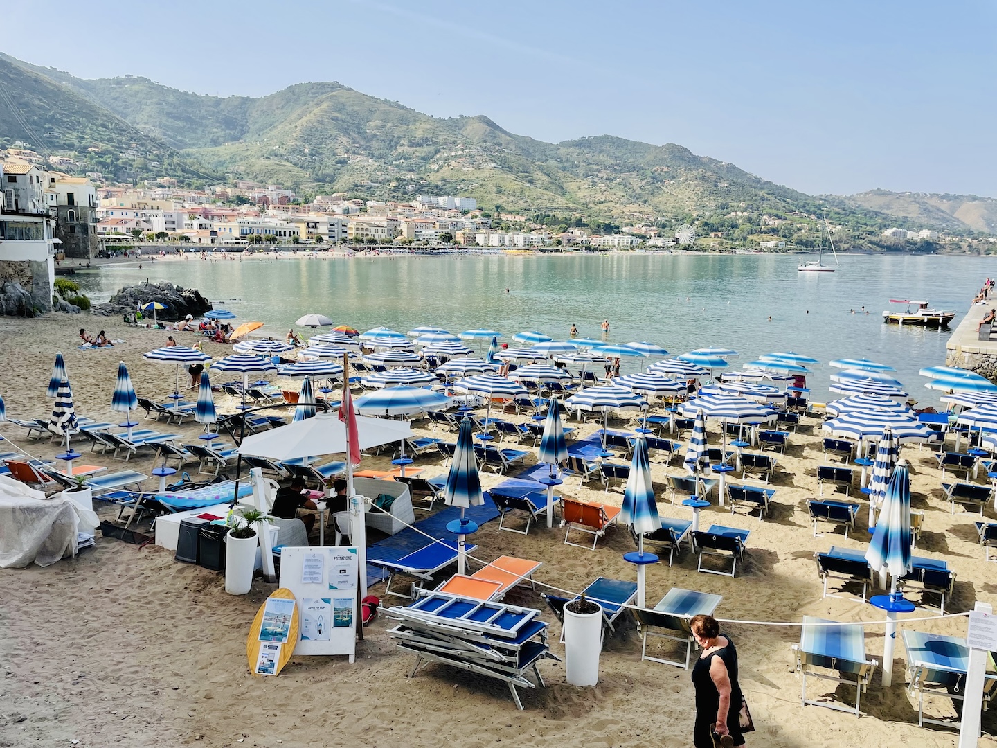 Dozens of blue and white umbrellas along with blue lounge chairs await visitors on a beach in Cefalu, Sicily.