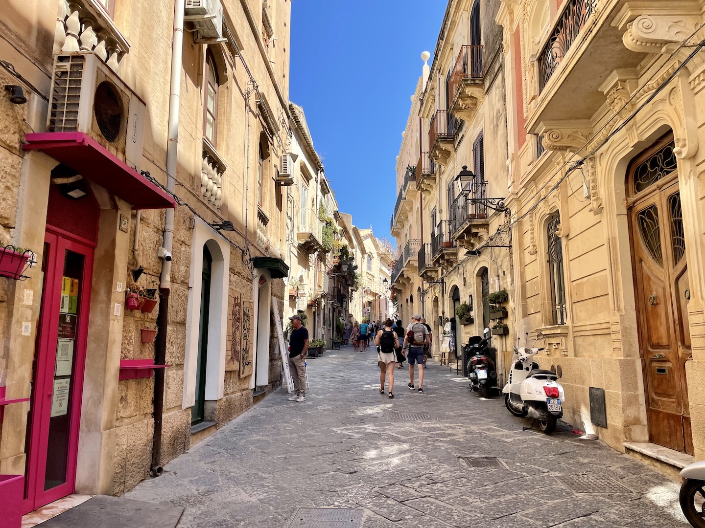 A couple holds hands as they walk down a pedestrian-only street in Ortigia, Sicily.