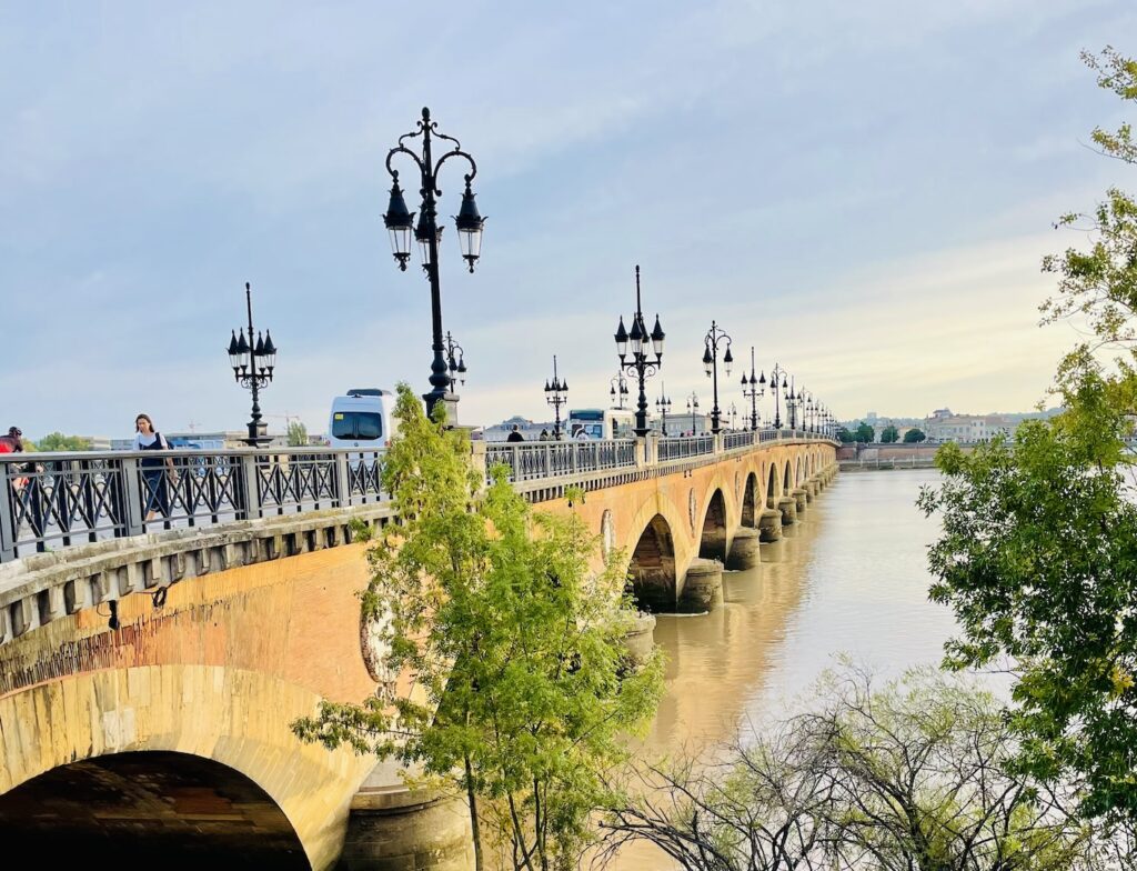 People and vehicles traverse the Pont de Pierre bridge in Bordeaux, France.